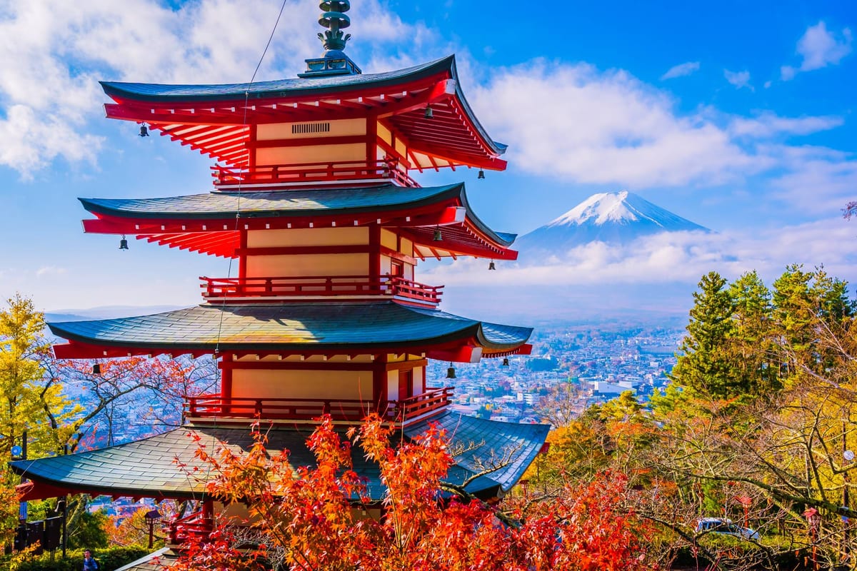 A red pagoda framed by autumn maple leaves, with Mount Fuji rising behind it