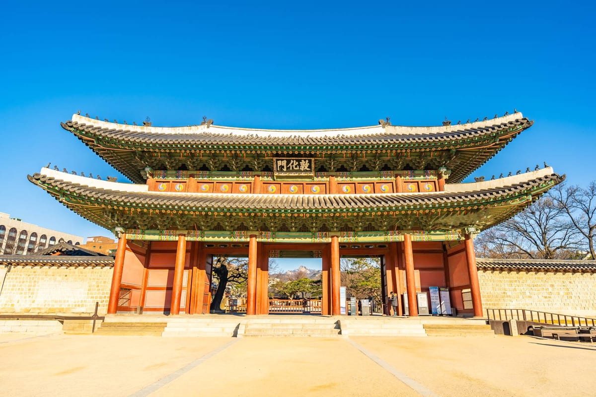 A traditional Korean palace gate with a tiled roof under a clear blue sky