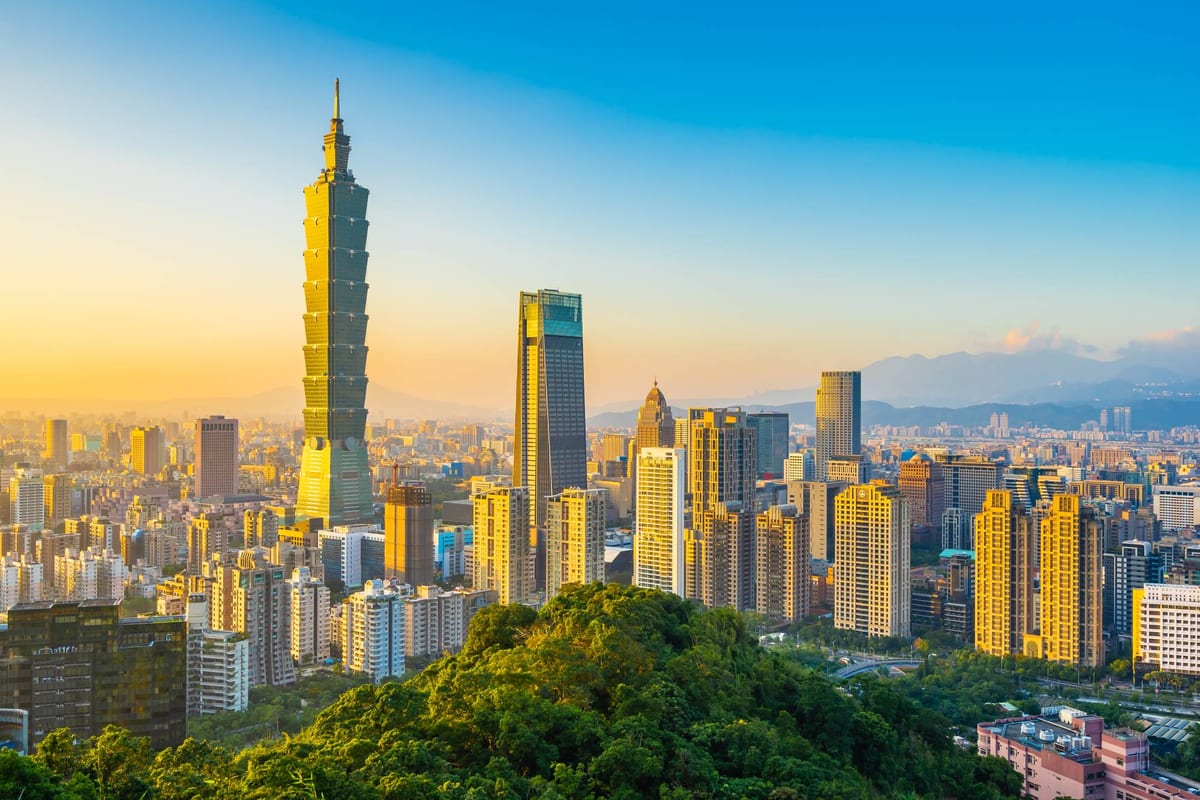 The Taipei skyline at golden hour, Taipei 101 rising above the city with green hills in front