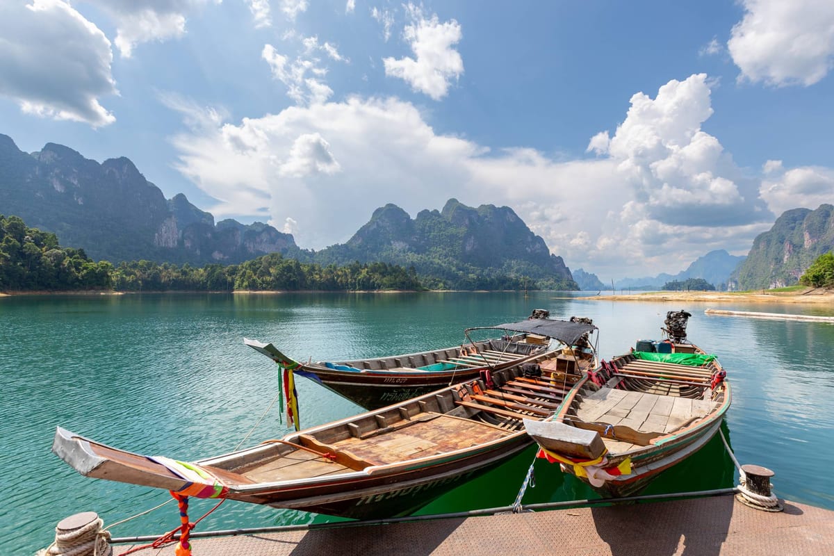 Wooden longtail boats moored on a calm lake ringed by limestone karst mountains